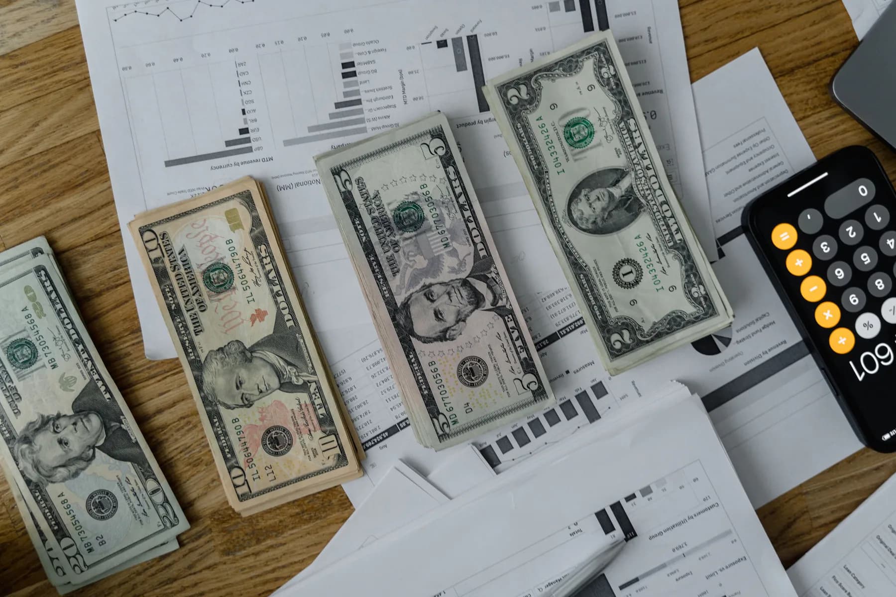 Cash, financial papers and a calculator on a desk.
