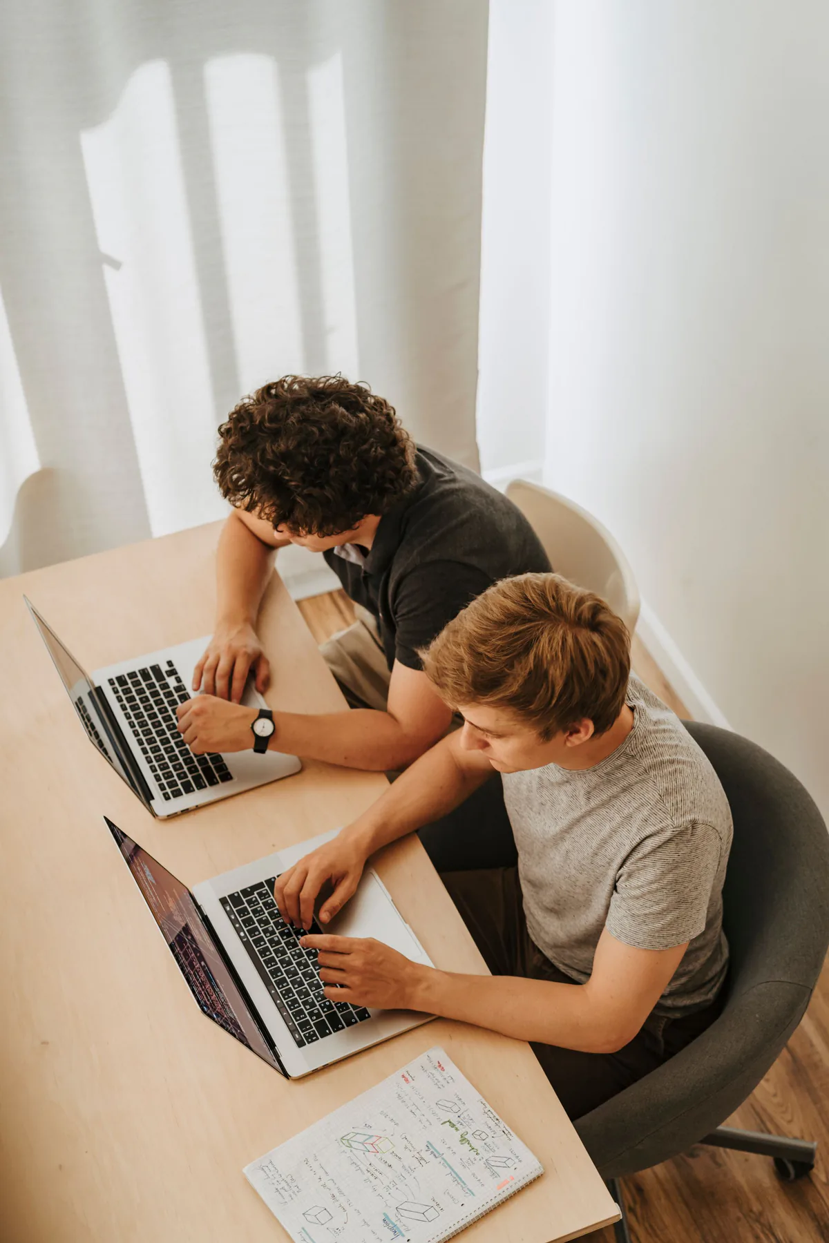 Two software developers collaborating on laptops in Minsk.