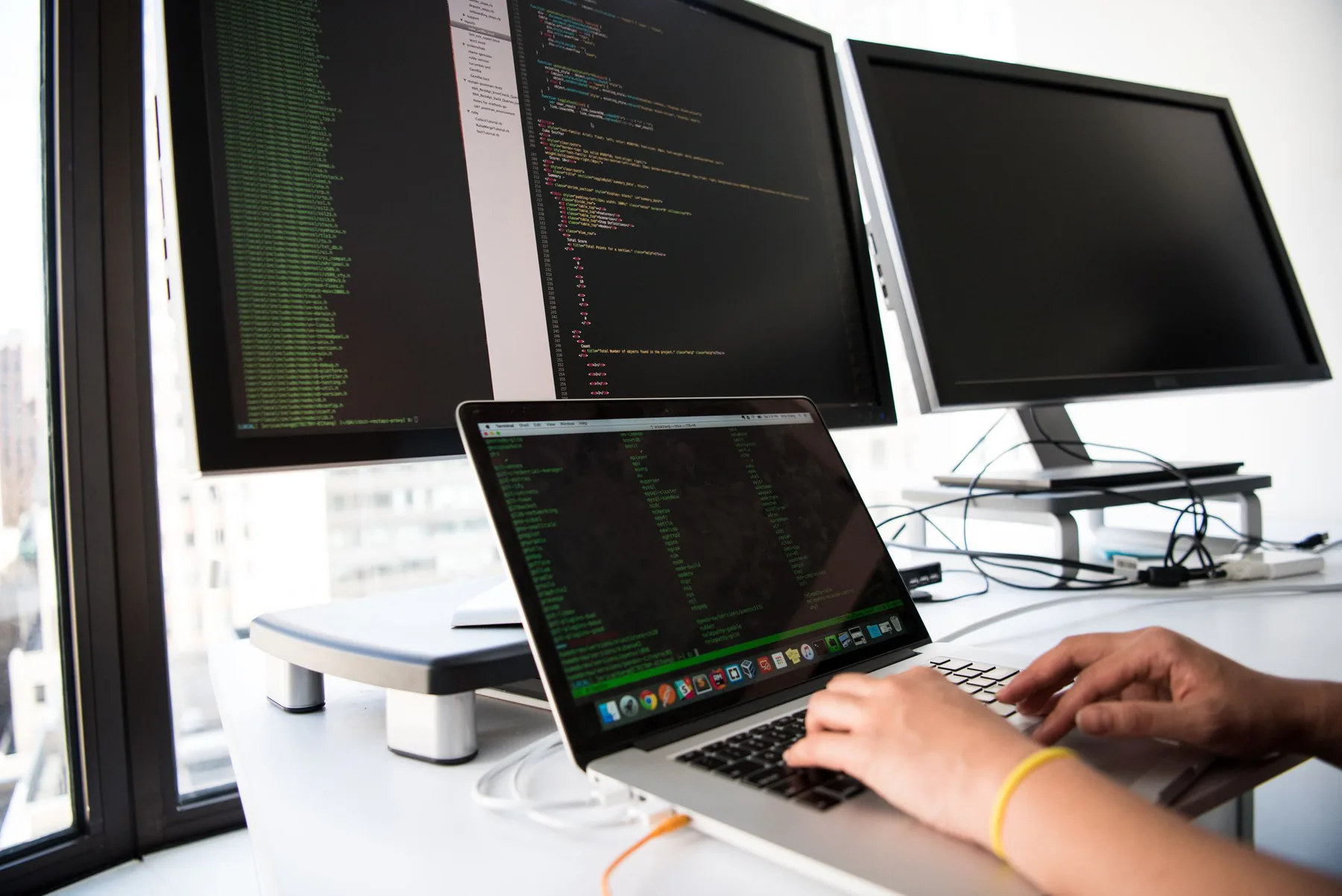 Developer workstation with code on multiple screens.