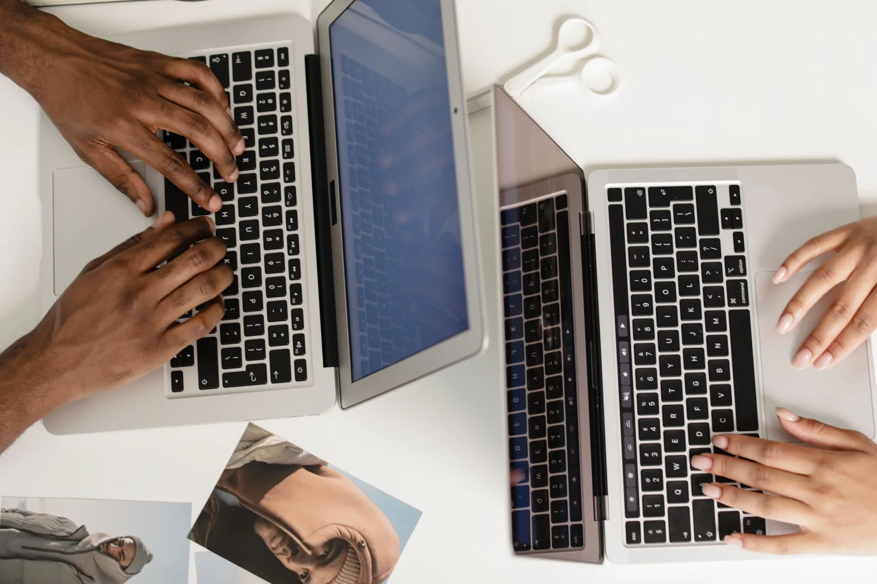 Two people working on laptops, viewed from above.